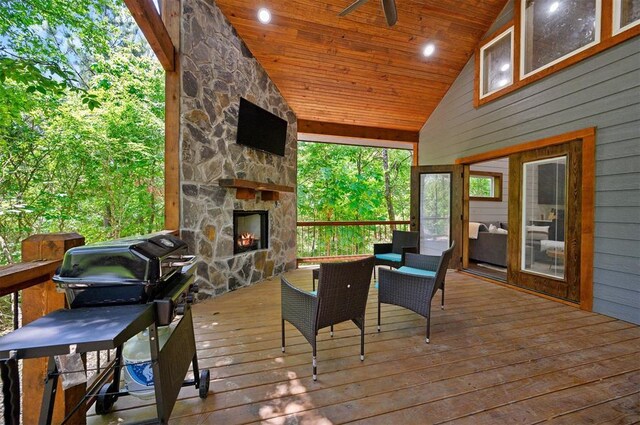 wooden deck featuring ceiling fan, a grill, and an outdoor stone fireplace