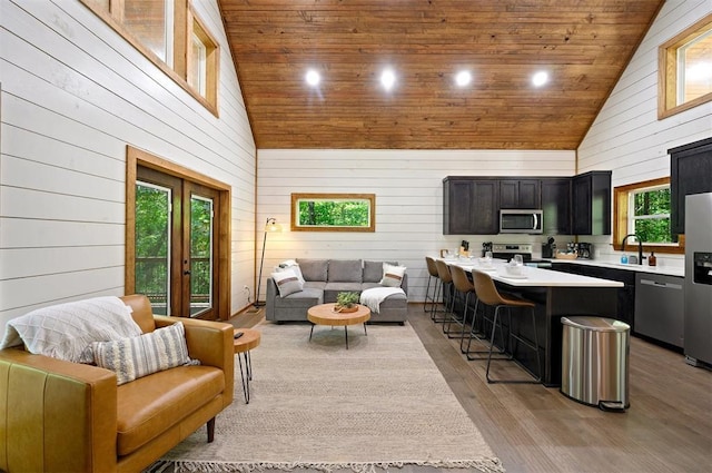 living room featuring light hardwood / wood-style floors, wooden walls, and high vaulted ceiling