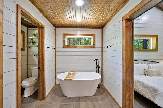 bathroom featuring toilet, wooden ceiling, wood walls, and a bathing tub