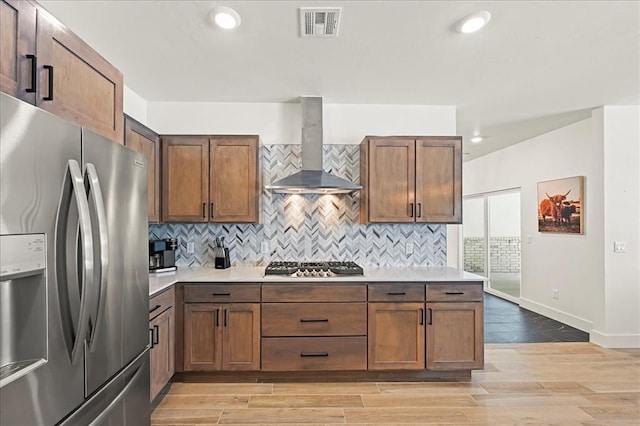 kitchen with tasteful backsplash, wall chimney exhaust hood, and stainless steel appliances