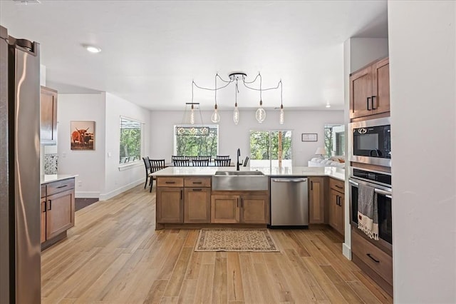 kitchen with kitchen peninsula, sink, decorative light fixtures, and appliances with stainless steel finishes