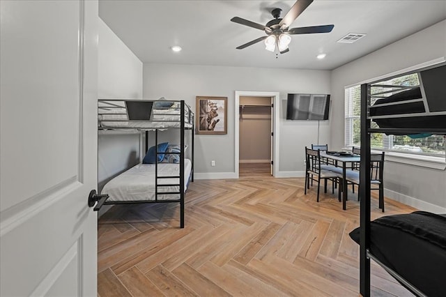 bedroom featuring ceiling fan, a closet, a walk in closet, and light parquet floors