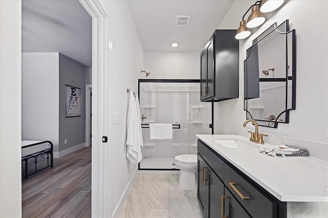 bathroom featuring a shower with door, vanity, and toilet