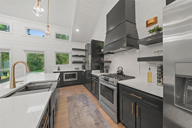 kitchen with decorative light fixtures, light wood-type flooring, custom range hood, and stainless steel appliances