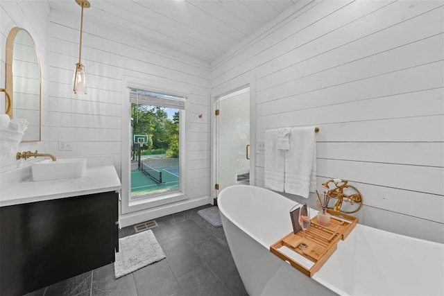 bathroom with tile patterned floors, wooden walls, a bathtub, and vanity