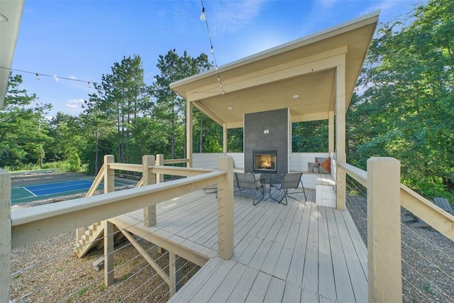 wooden terrace featuring tennis court and a fireplace