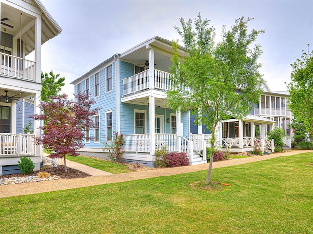 view of front of property featuring a balcony, covered porch, a front lawn, and a ceiling fan