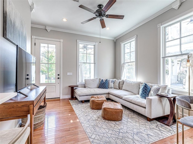 living room with ornamental molding, recessed lighting, light wood-style floors, and baseboards