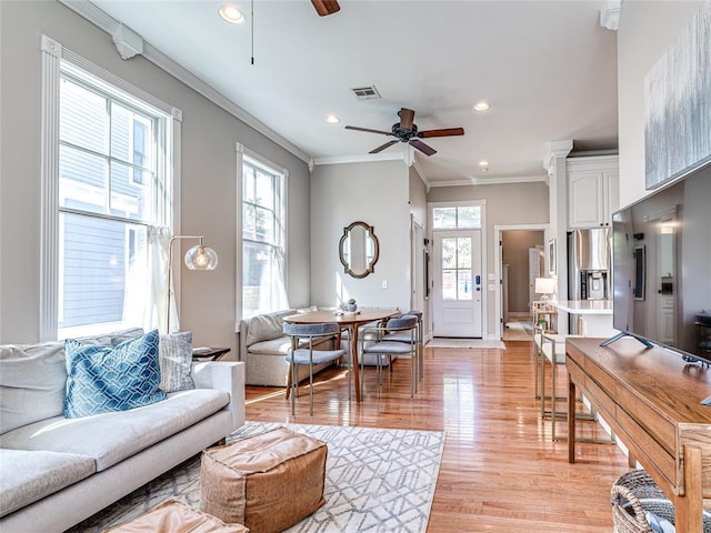 living room featuring crown molding, visible vents, ceiling fan, and light wood finished floors