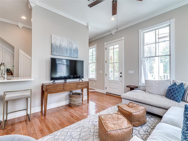 living room with baseboards, a ceiling fan, crown molding, light wood-style floors, and recessed lighting