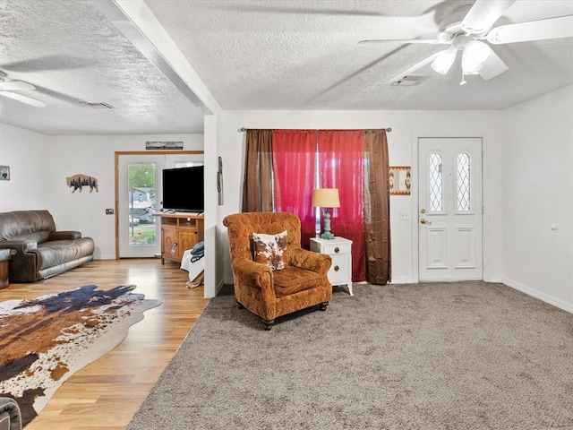 living room with ceiling fan, wood-type flooring, and a textured ceiling