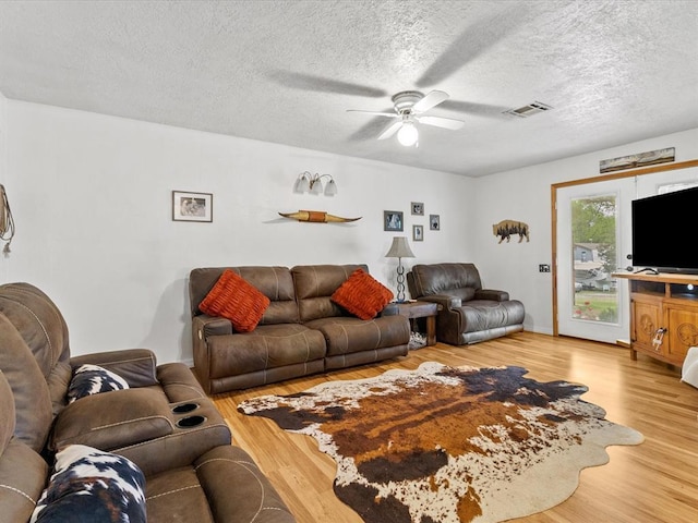 living room with ceiling fan, hardwood / wood-style floors, and a textured ceiling