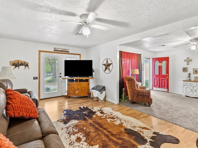 living room featuring ceiling fan, light wood-type flooring, a textured ceiling, and french doors