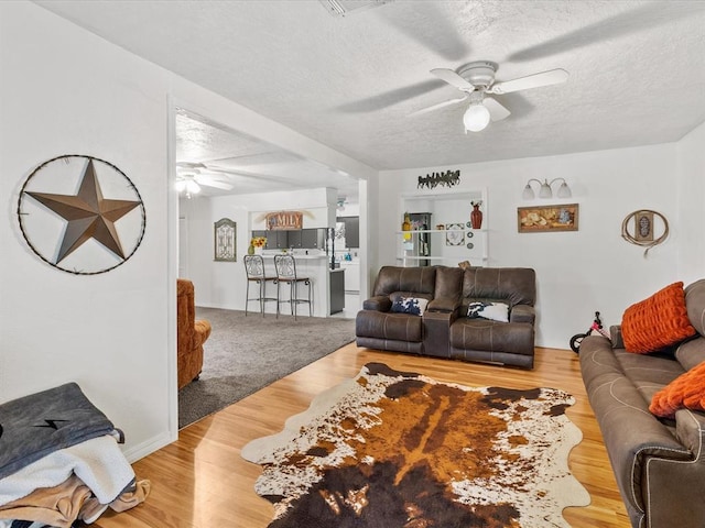 living room with ceiling fan, wood-type flooring, and a textured ceiling