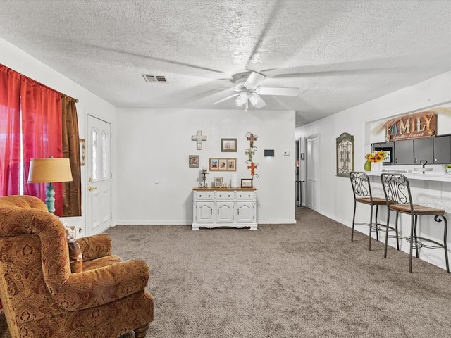 sitting room with ceiling fan, carpet floors, and a textured ceiling