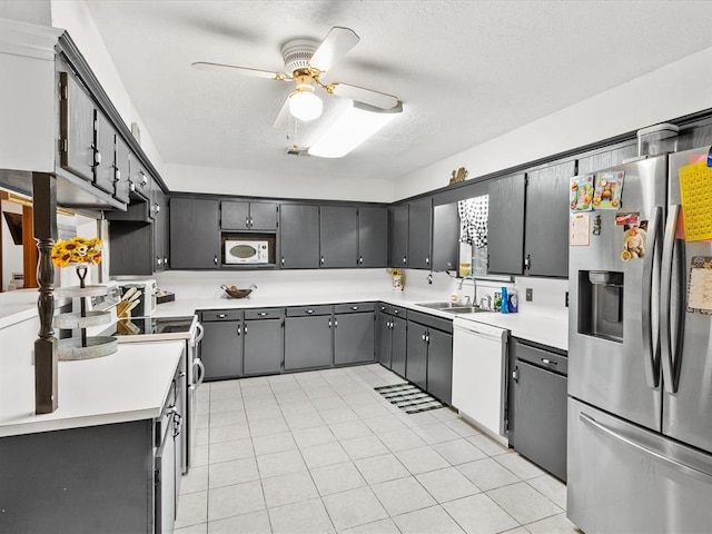 kitchen with appliances with stainless steel finishes, a textured ceiling, ceiling fan, sink, and light tile patterned floors