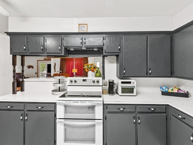 kitchen with white electric range oven, kitchen peninsula, gray cabinetry, and exhaust hood