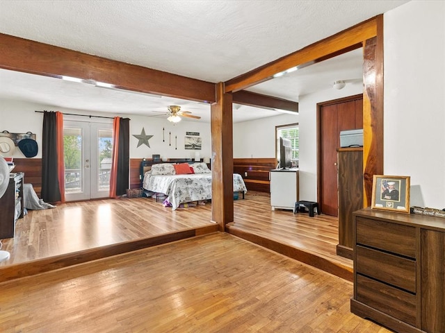 bedroom with beam ceiling, french doors, access to outside, and light wood-type flooring