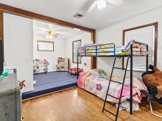 bedroom featuring hardwood / wood-style floors, ceiling fan, and a textured ceiling