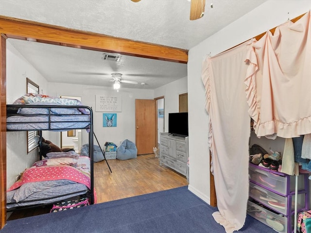 bedroom with hardwood / wood-style floors, a textured ceiling, and ceiling fan