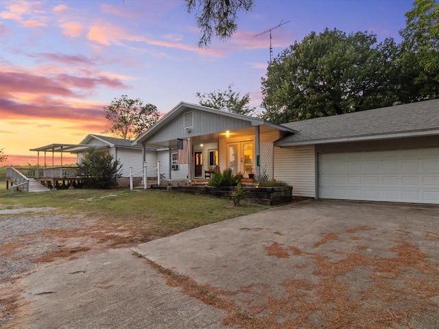 view of front of property featuring a lawn, covered porch, and a garage