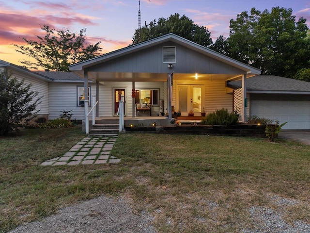 view of front of house featuring a porch, a garage, and a yard