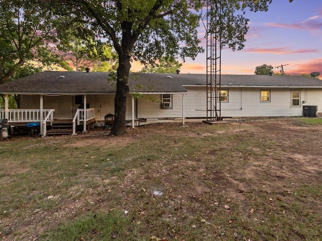 back house at dusk featuring a yard, central AC, and a deck