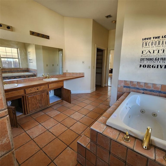 bathroom with tile patterned floors, vanity, and a relaxing tiled tub