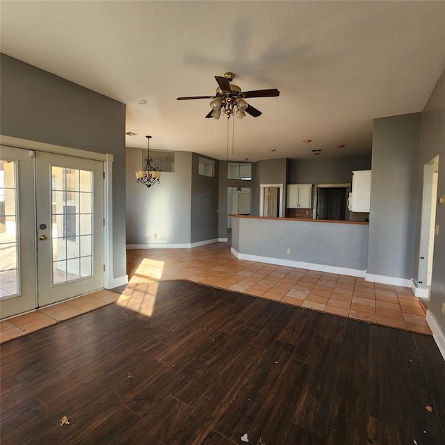 unfurnished living room featuring light hardwood / wood-style flooring, ceiling fan with notable chandelier, and french doors