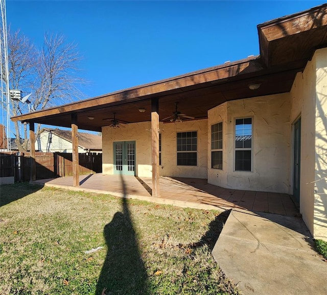 back of property with a yard, ceiling fan, and a patio area