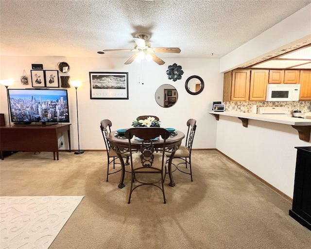 dining room featuring ceiling fan, light colored carpet, and a textured ceiling