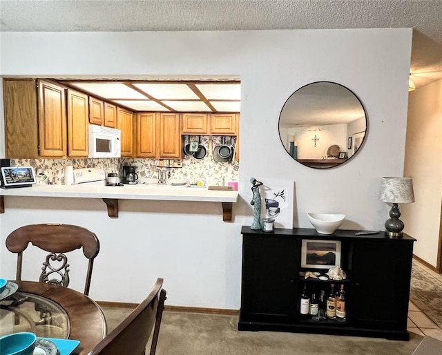 kitchen featuring a textured ceiling, stove, kitchen peninsula, and a kitchen breakfast bar