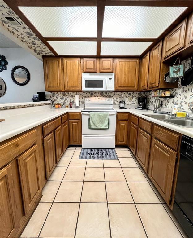 kitchen with tasteful backsplash, light tile patterned floors, sink, and white appliances