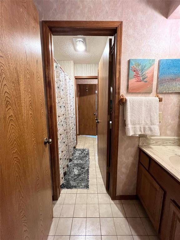 bathroom with a textured ceiling, tile patterned floors, and vanity