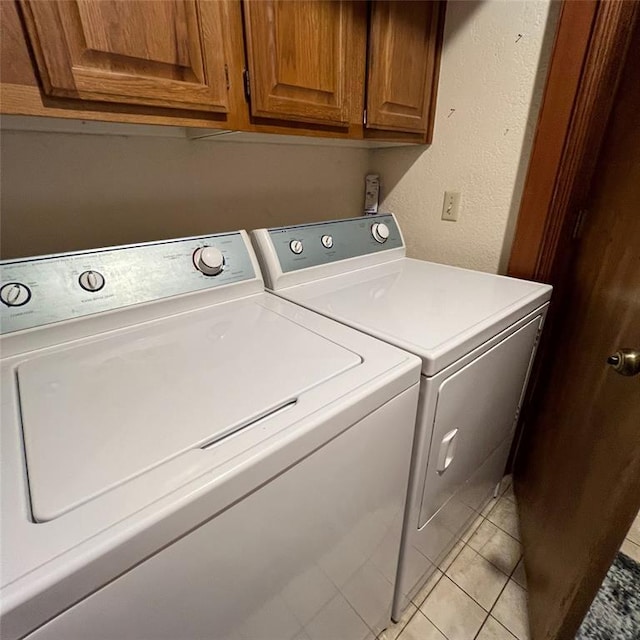 washroom with light tile patterned floors, cabinets, and washer and dryer