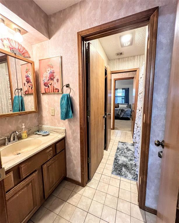 bathroom with a textured ceiling, tile patterned flooring, and vanity