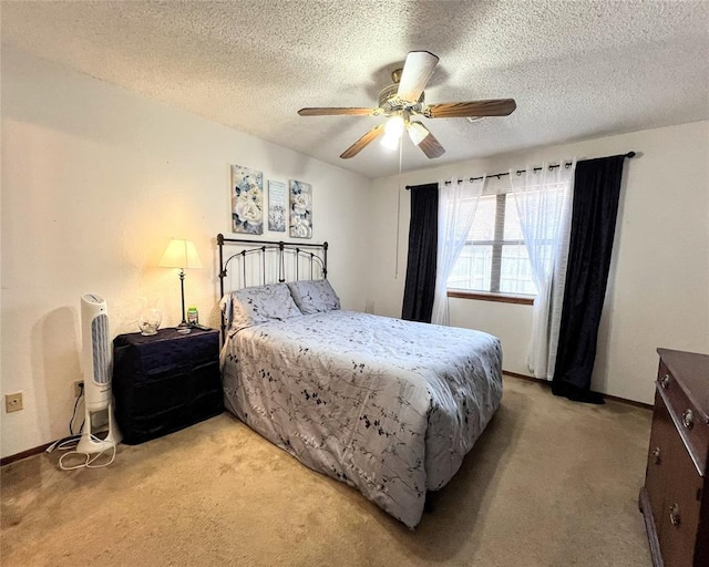 bedroom featuring ceiling fan, light colored carpet, and a textured ceiling