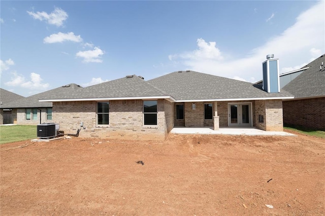11813 Ethan Mark Dr, Yukon, OK 73099 - back of property with french doors, central AC unit, a patio area, brick siding, and a chimney