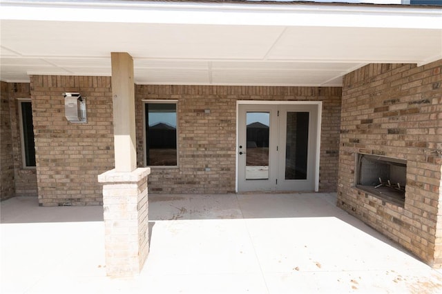 11813 Ethan Mark Dr, Yukon, OK 73099 - view of exterior entry featuring an outdoor brick fireplace, a patio area, and brick siding