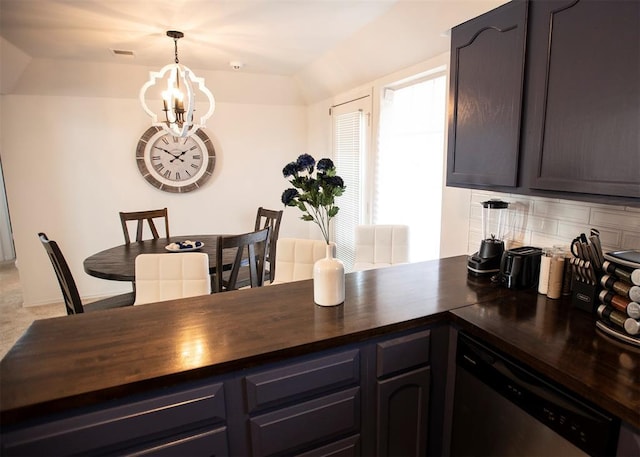 kitchen featuring tasteful backsplash, a notable chandelier, lofted ceiling, dishwasher, and hanging light fixtures