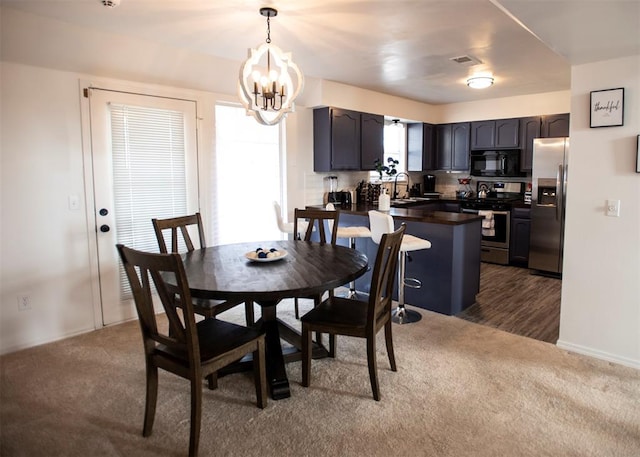 carpeted dining room with sink and an inviting chandelier