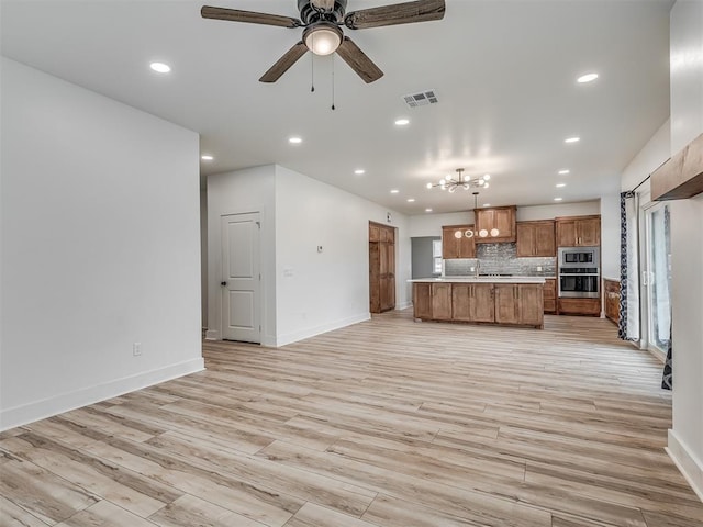 kitchen with light wood-type flooring, backsplash, stainless steel appliances, ceiling fan, and pendant lighting