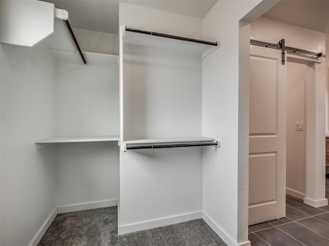 spacious closet featuring a barn door and dark tile patterned flooring