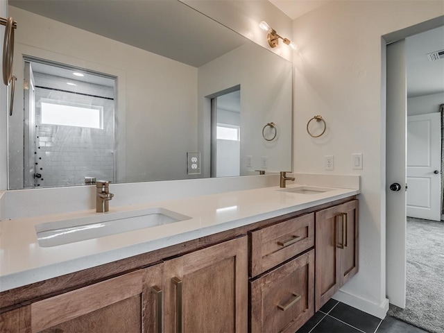 bathroom featuring tile patterned flooring, vanity, and a tile shower