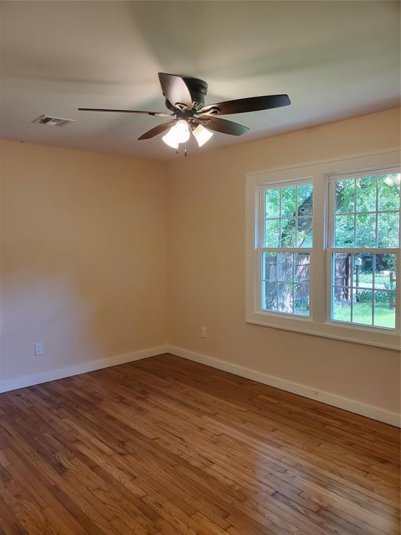 1021 W Apache St, Norman, OK 73069 - unfurnished room with plenty of natural light, wood finished floors, a ceiling fan, and baseboards