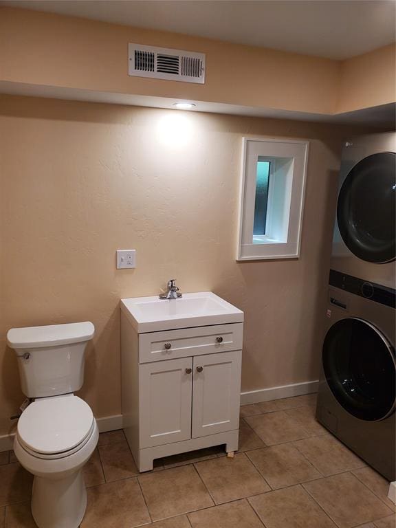 1021 W Apache St, Norman, OK 73069 - laundry room with stacked washing machine and dryer, light tile patterned floors, and baseboards
