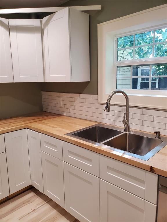 1021 W Apache St, Norman, OK 73069 - kitchen featuring wooden counters, a sink, decorative backsplash, white cabinets, and light wood-type flooring
