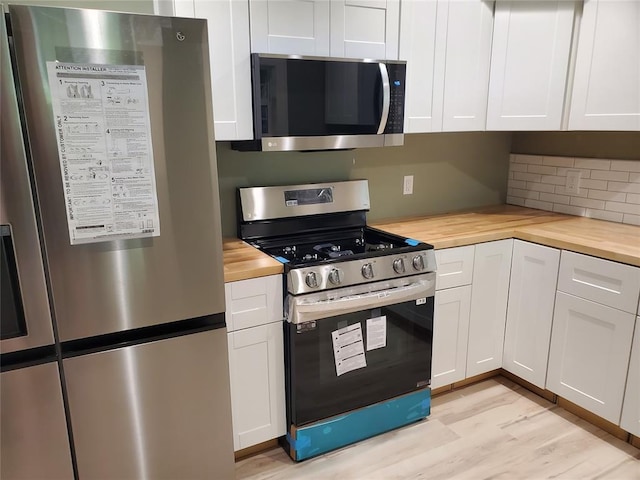 1021 W Apache St, Norman, OK 73069 - kitchen with appliances with stainless steel finishes, wooden counters, and white cabinetry