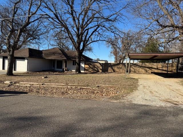 exterior space with a carport, fence, and dirt driveway