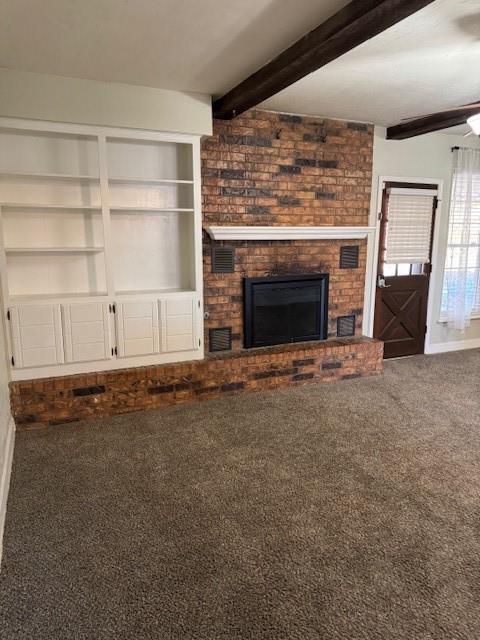 unfurnished living room featuring carpet floors, a fireplace, beamed ceiling, and a ceiling fan